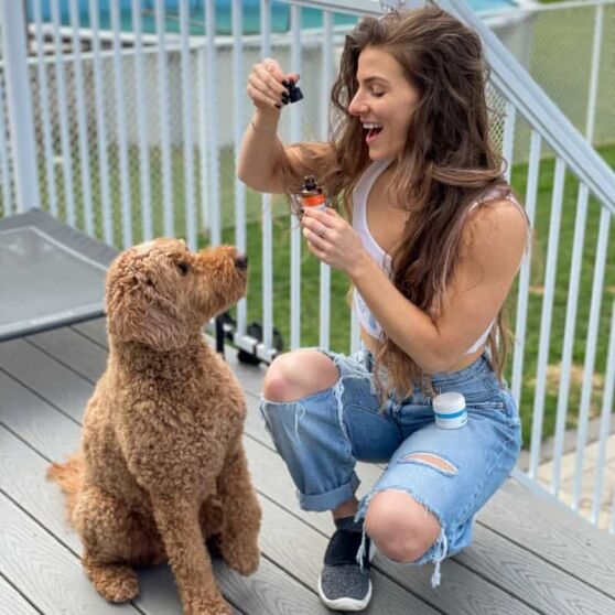 Woman giving CBD oil to her poodle